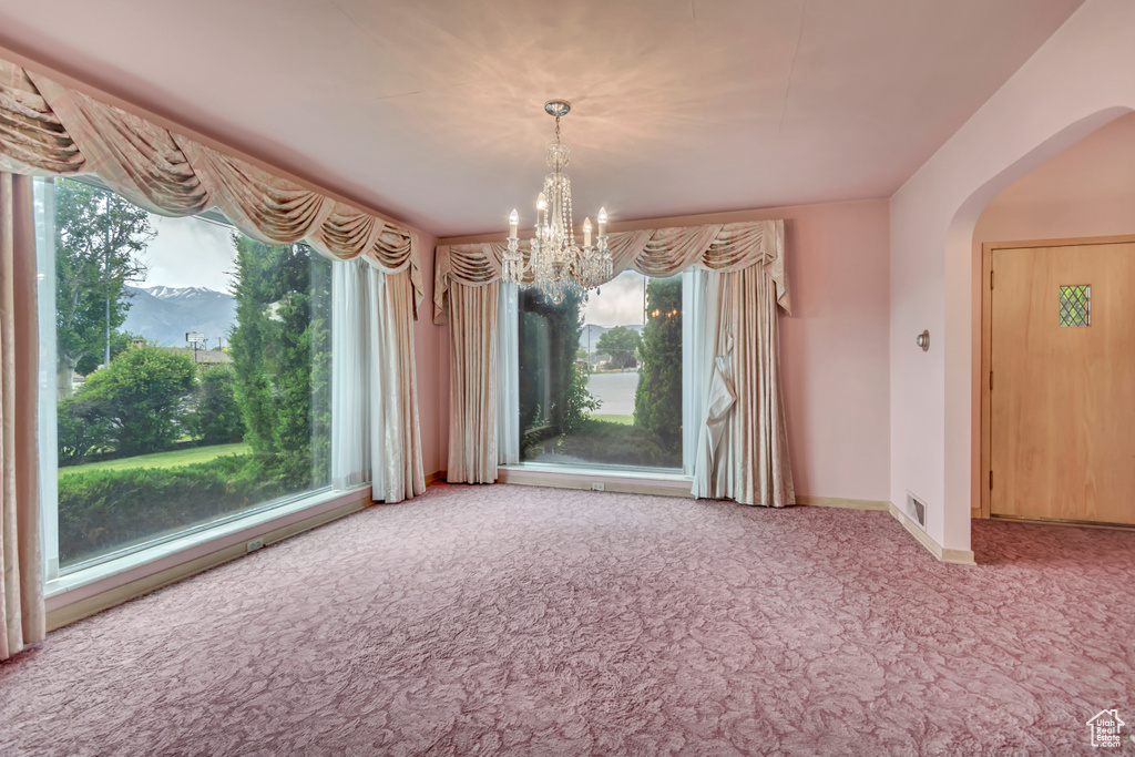 Unfurnished dining area featuring carpet, arched walkways, a chandelier, and baseboards