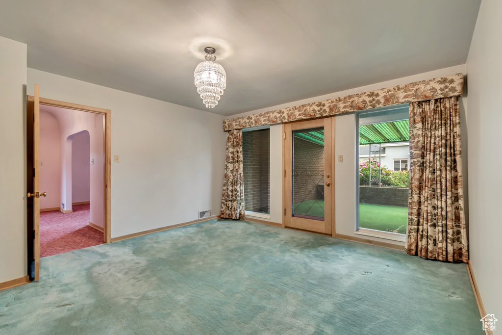Spare room featuring carpet floors, arched walkways, and baseboards