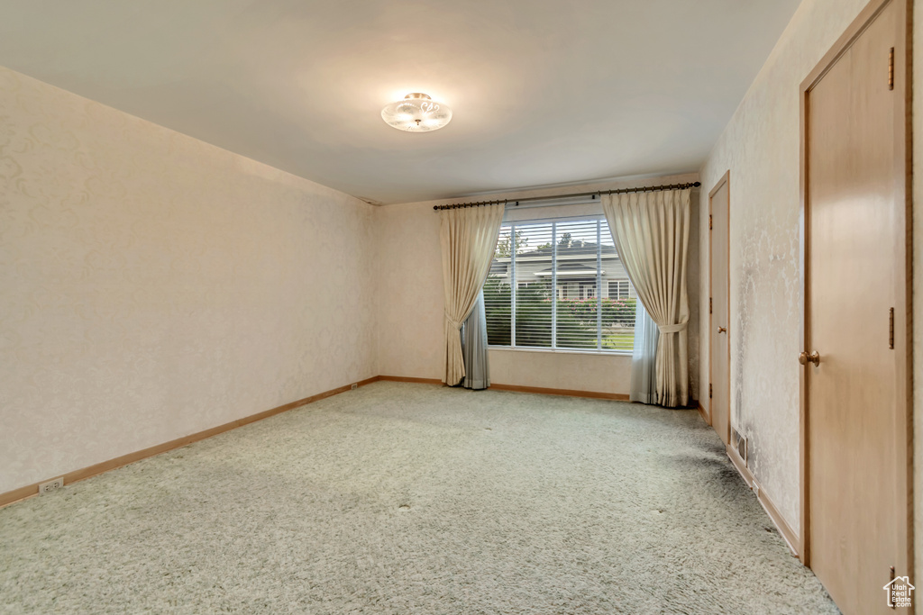 Unfurnished bedroom with light colored carpet and baseboards