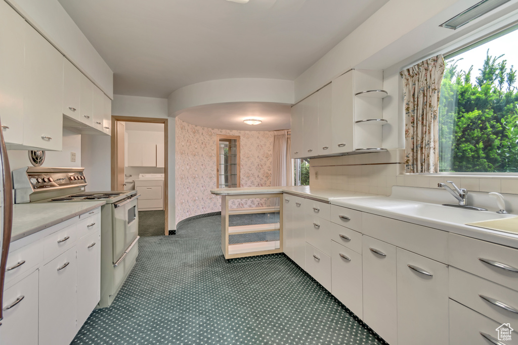 Kitchen with white electric range, light countertops, a sink, and white cabinets