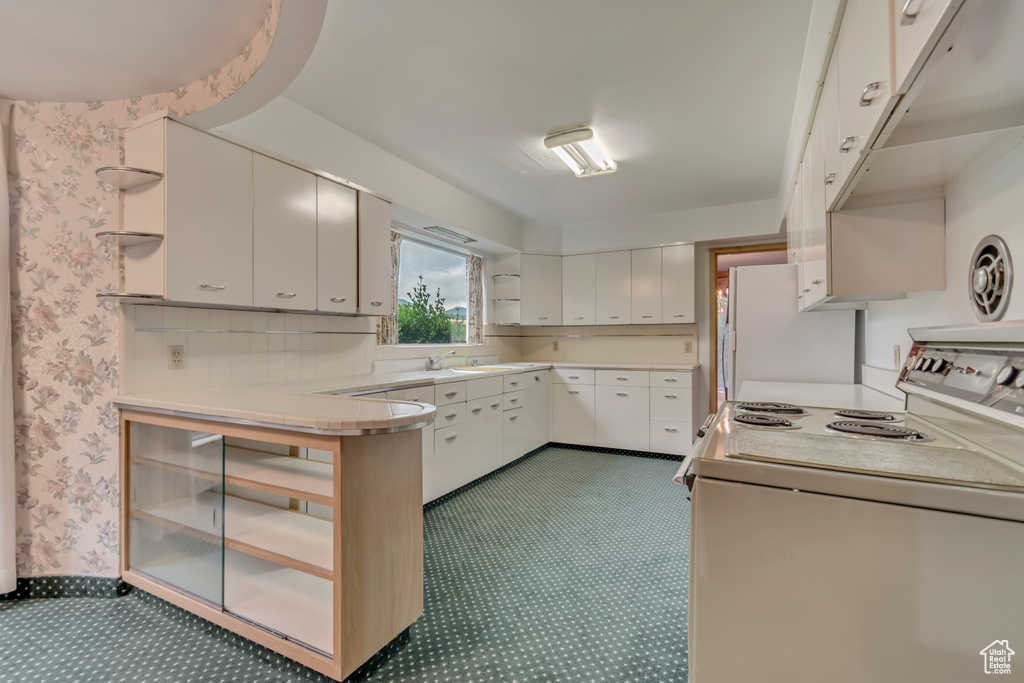 Kitchen featuring white appliances, light countertops, open shelves, wallpapered walls, and white cabinets
