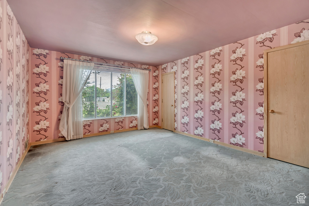 Carpeted spare room featuring wallpapered walls and baseboards