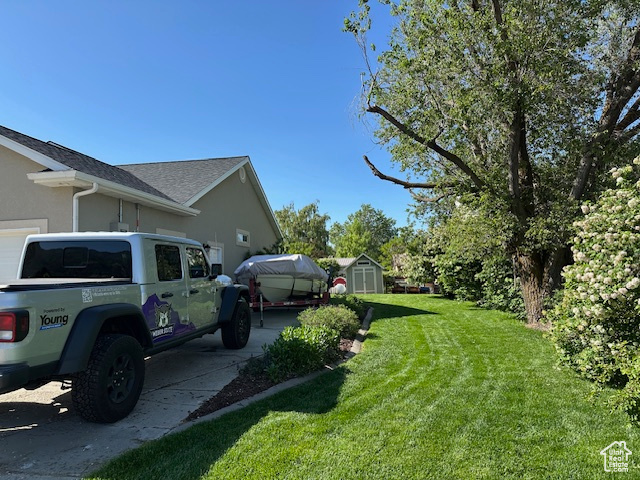 View of side of home featuring a lawn, stucco siding, and a shingled roof