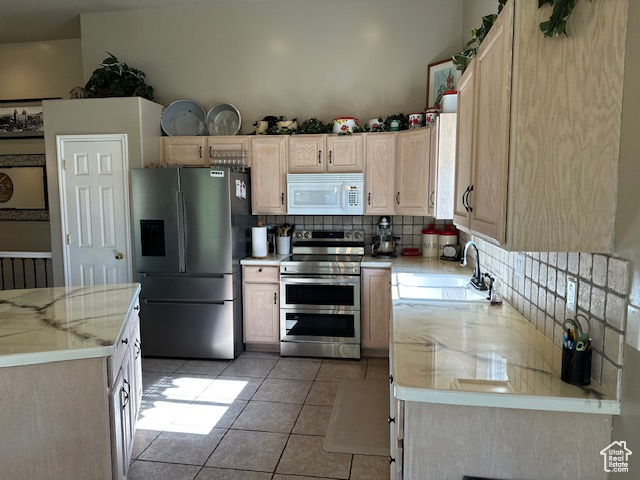 Kitchen with appliances with stainless steel finishes, a sink, backsplash, light brown cabinetry, and light tile patterned floors