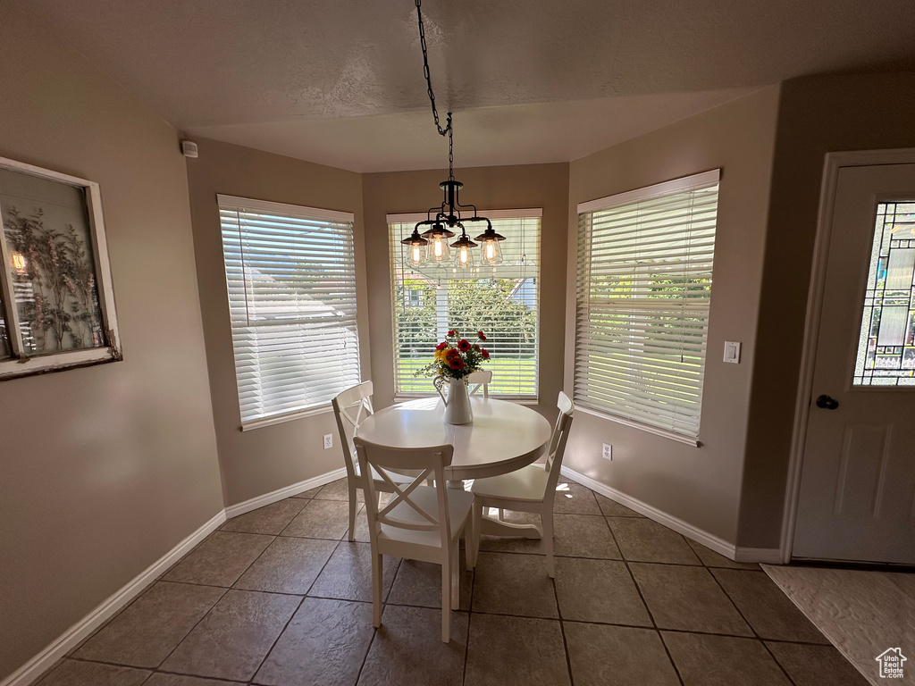 Dining room with a chandelier, tile patterned floors, and baseboards
