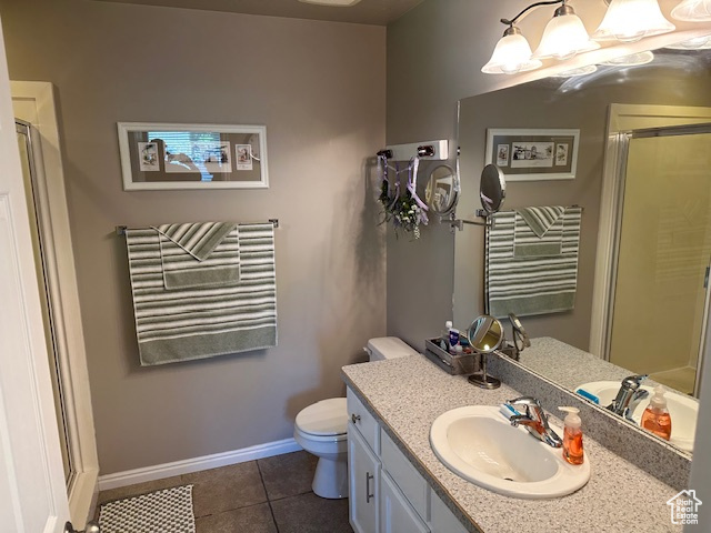 Bathroom with vanity, a stall shower, toilet, tile patterned floors, and baseboards