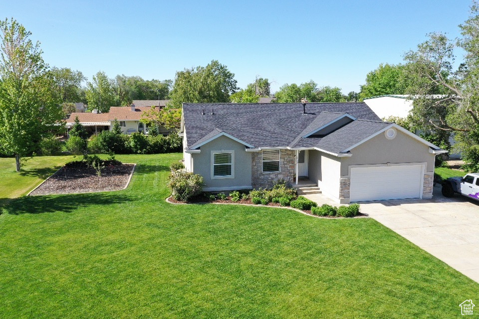 Ranch-style house with stone siding, an attached garage, driveway, a front lawn, and a shingled roof