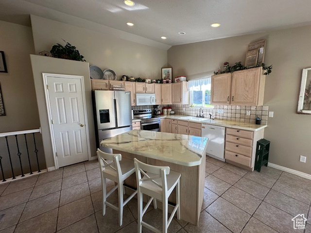 Kitchen with appliances with stainless steel finishes, light brown cabinets, tasteful backsplash, lofted ceiling, and light tile patterned floors