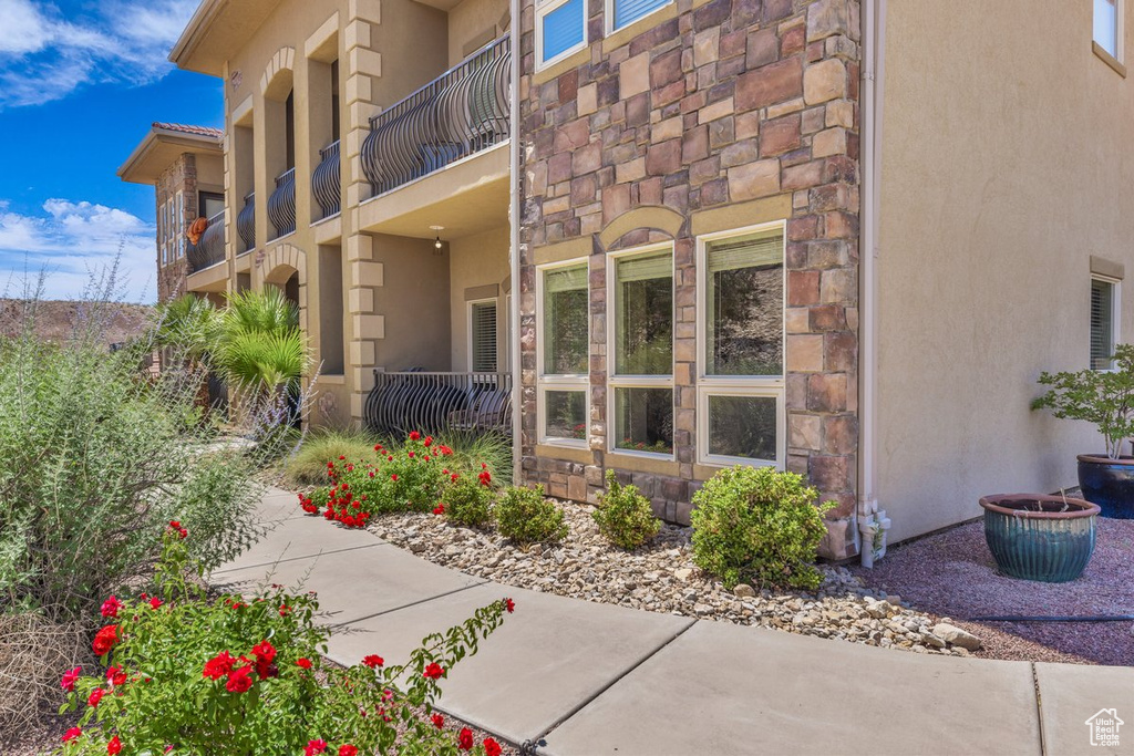 Doorway to property with stone siding, stucco siding, and a balcony