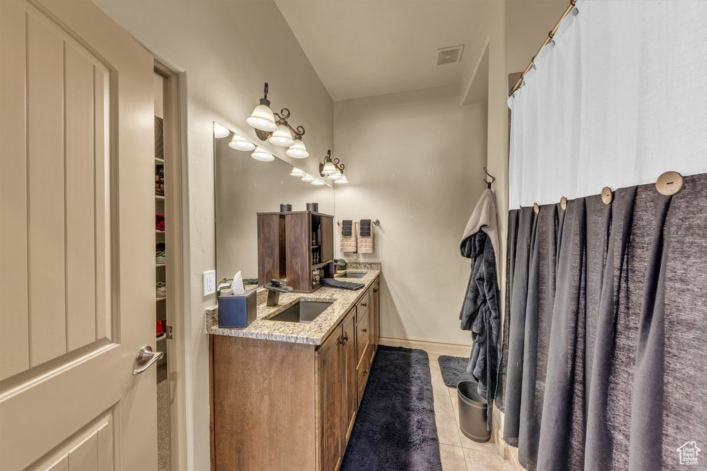 Full bath featuring tile patterned flooring, double vanity, and baseboards