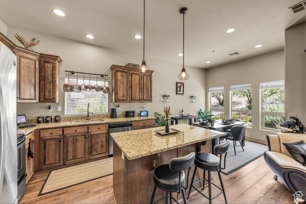 Kitchen featuring a sink, stainless steel dishwasher, light wood-style floors, light stone counters, and recessed lighting