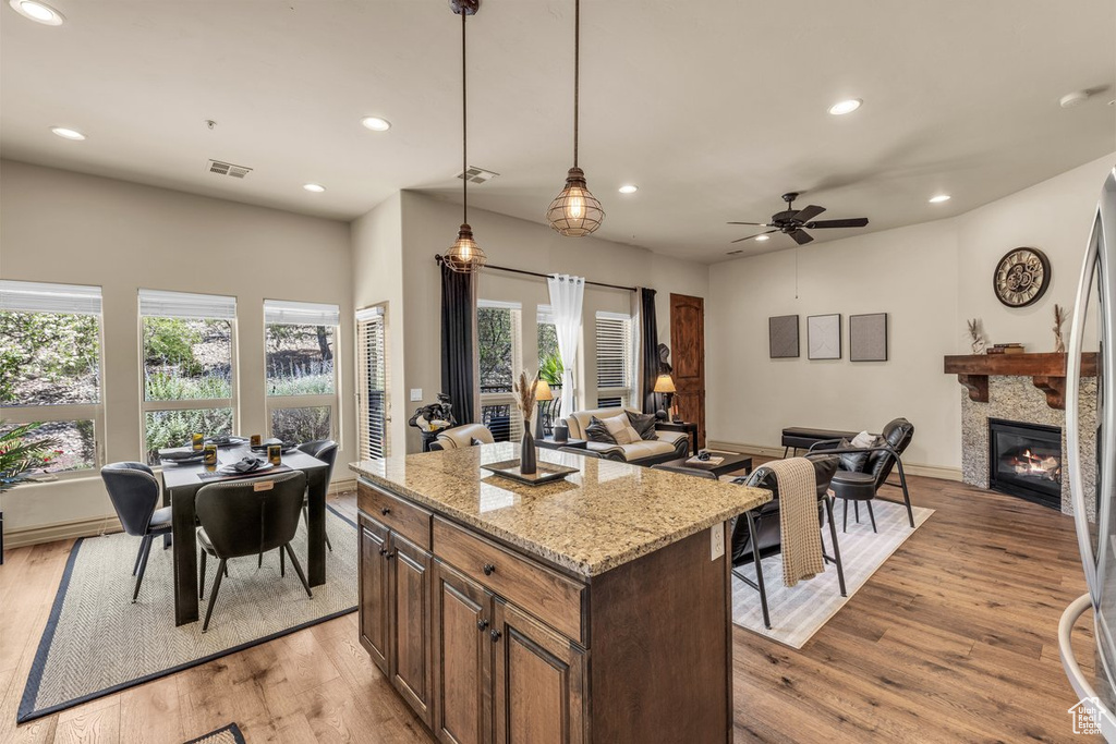 Kitchen with recessed lighting, open floor plan, light wood finished floors, a glass covered fireplace, and a ceiling fan