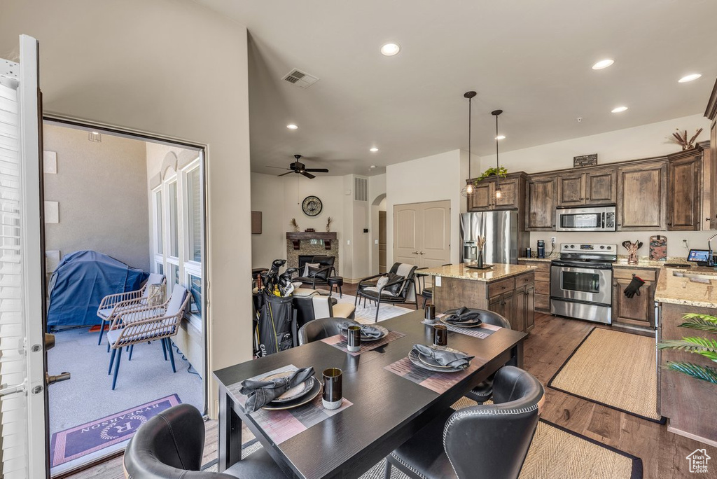 Dining area with dark wood-style floors, recessed lighting, a ceiling fan, and arched walkways