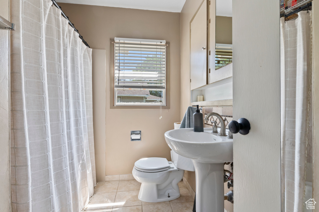 Full bath featuring toilet, tile patterned flooring, baseboards, and curtained shower