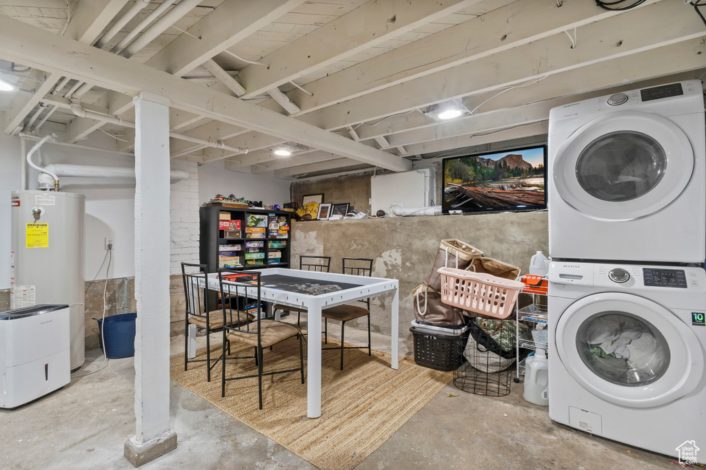 Laundry room featuring water heater and stacked washer and clothes dryer