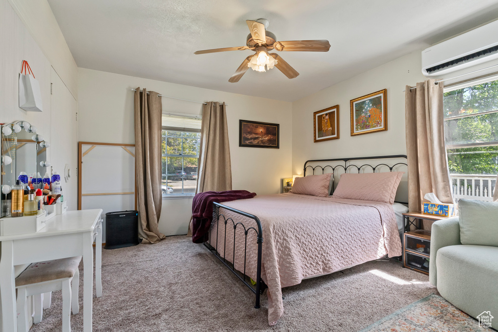 Bedroom with a wall mounted AC, light carpet, and a ceiling fan