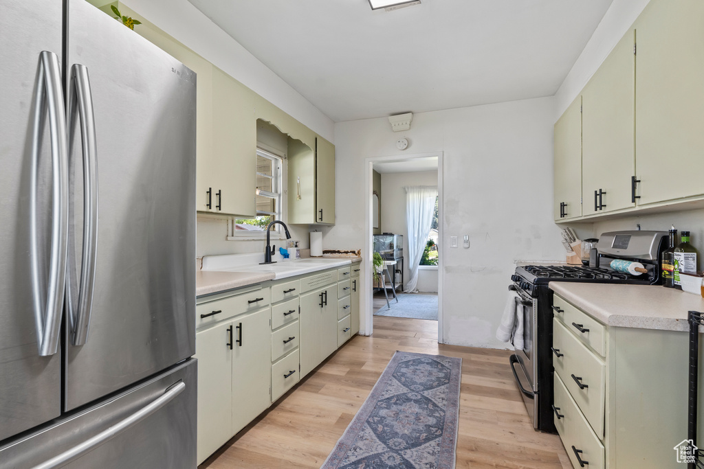 Kitchen with stainless steel appliances, light countertops, light wood finished floors, and a sink