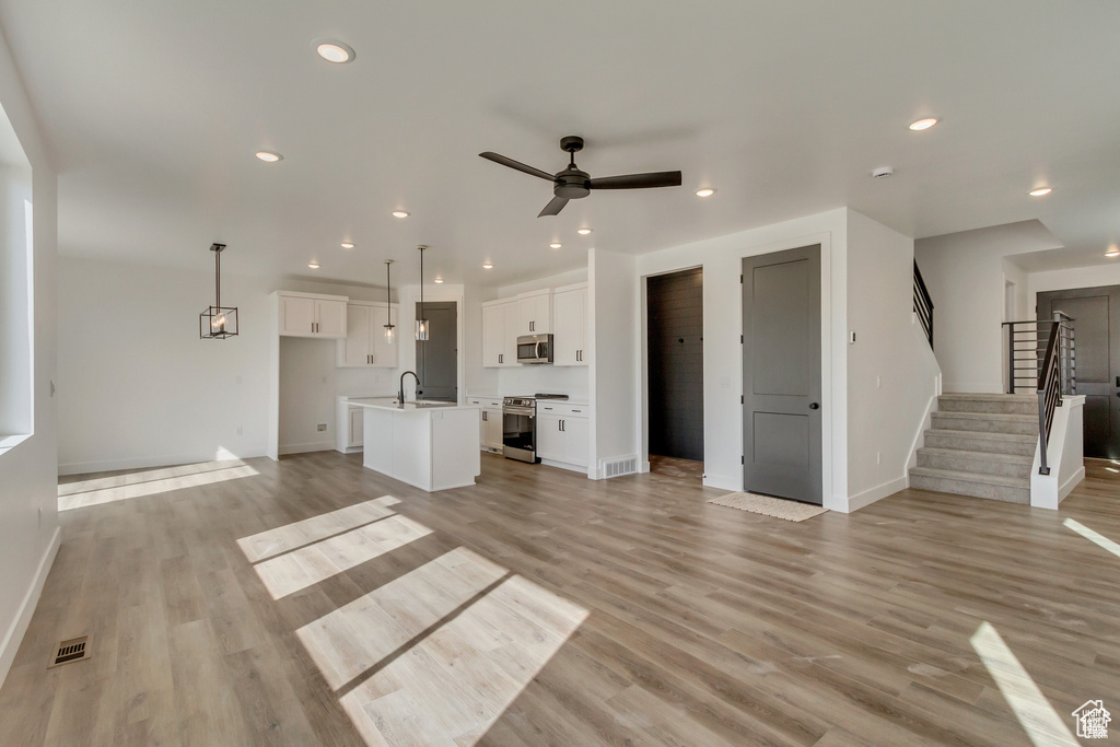 Unfurnished living room featuring baseboards, a ceiling fan, light wood finished floors, and recessed lighting