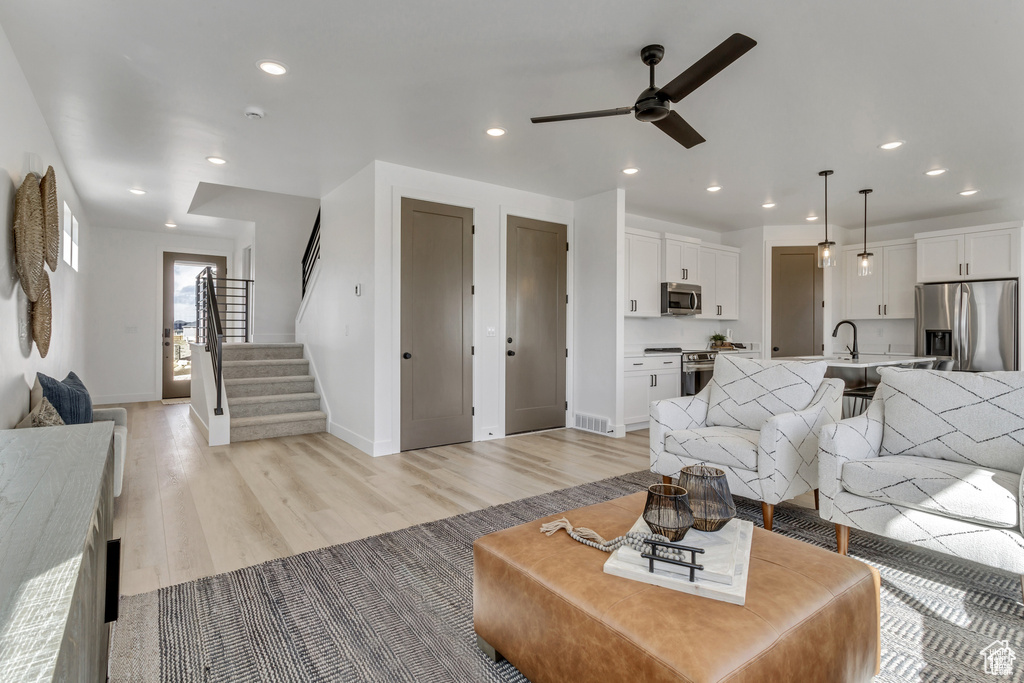 Living room with a ceiling fan, light wood-style flooring, baseboards, recessed lighting, and stairway