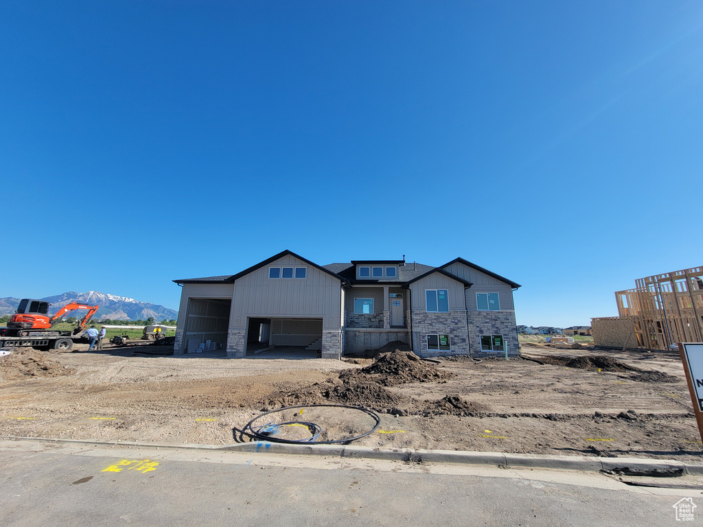 Property under construction with stone siding, a garage, and a mountain view