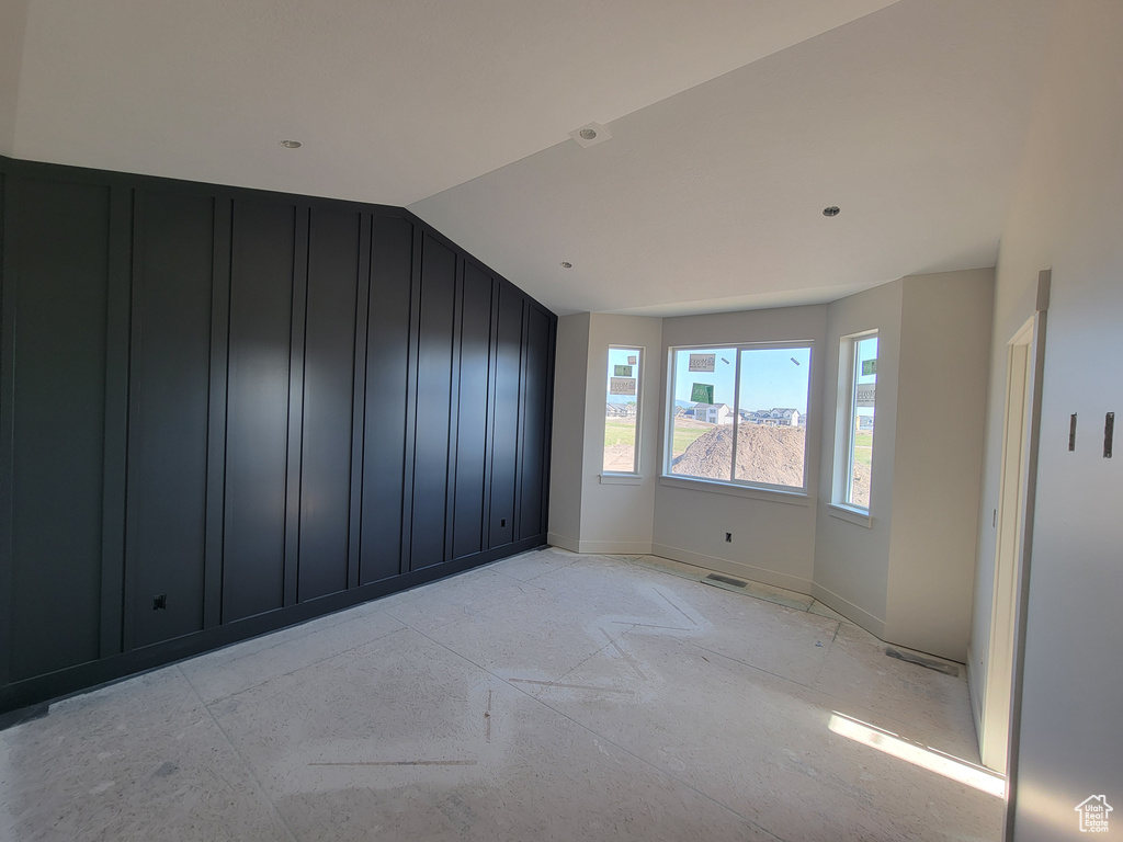 Spare room with a decorative wall, lofted ceiling, and baseboards