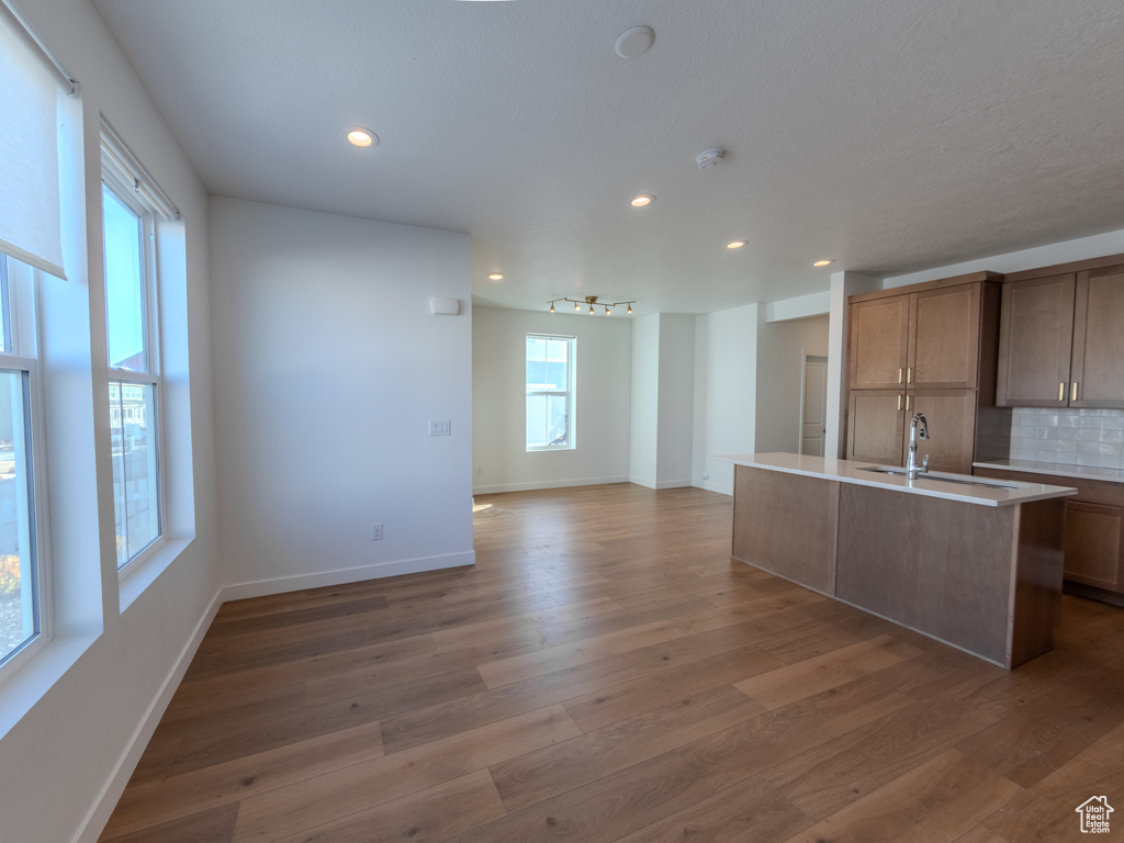 Kitchen featuring recessed lighting, wood finished floors, decorative backsplash, open floor plan, and baseboards