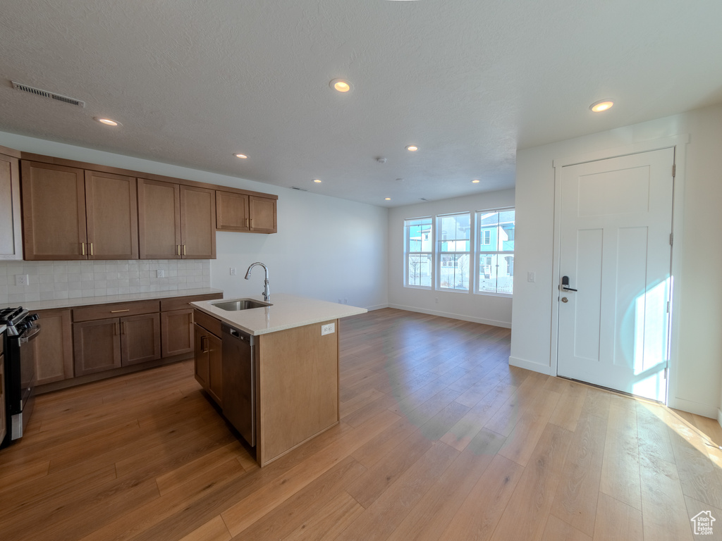 Kitchen with dishwasher, a sink, backsplash, light wood-type flooring, and recessed lighting
