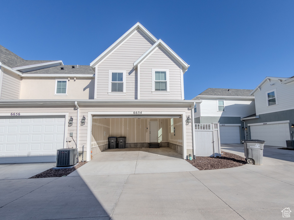 View of front of house with concrete driveway, a garage, and central AC