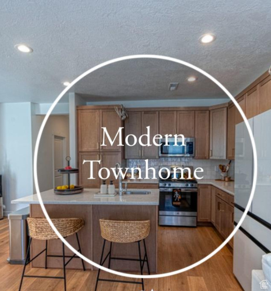 Kitchen featuring appliances with stainless steel finishes, a textured ceiling, recessed lighting, light wood-style floors, and tasteful backsplash