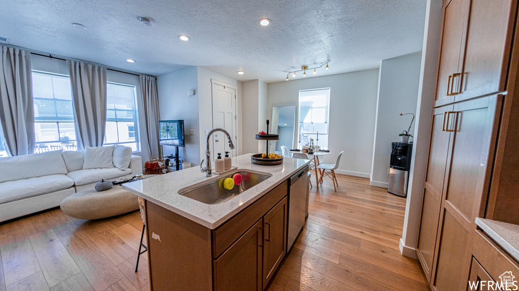 Kitchen with a sink, a breakfast bar area, light wood finished floors, plenty of natural light, and a textured ceiling