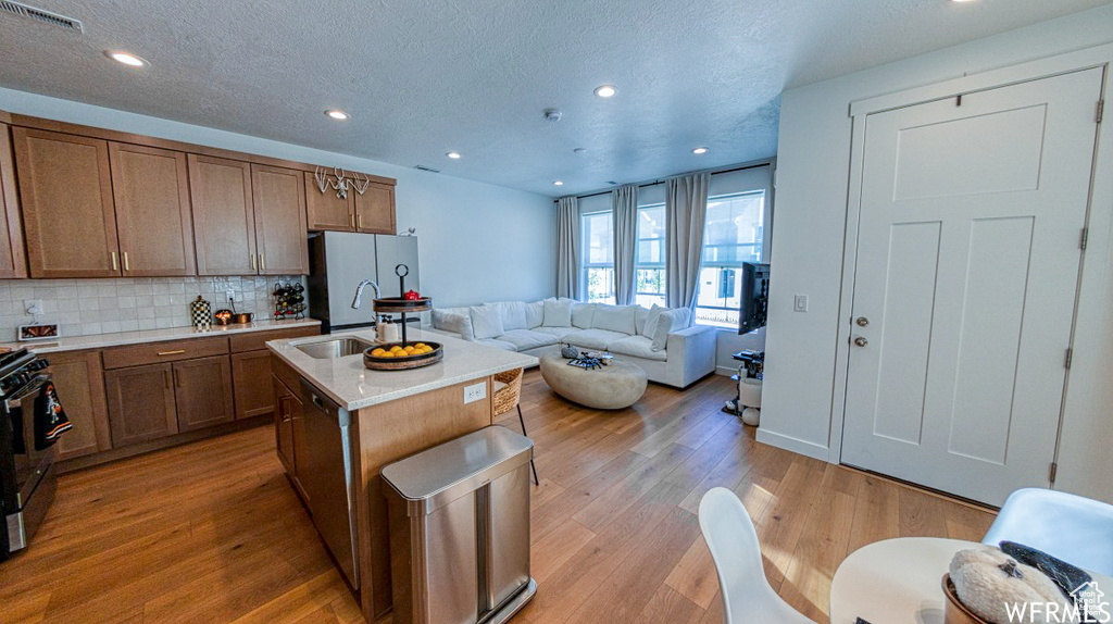Kitchen with freestanding refrigerator, gas range, tasteful backsplash, open floor plan, and a sink