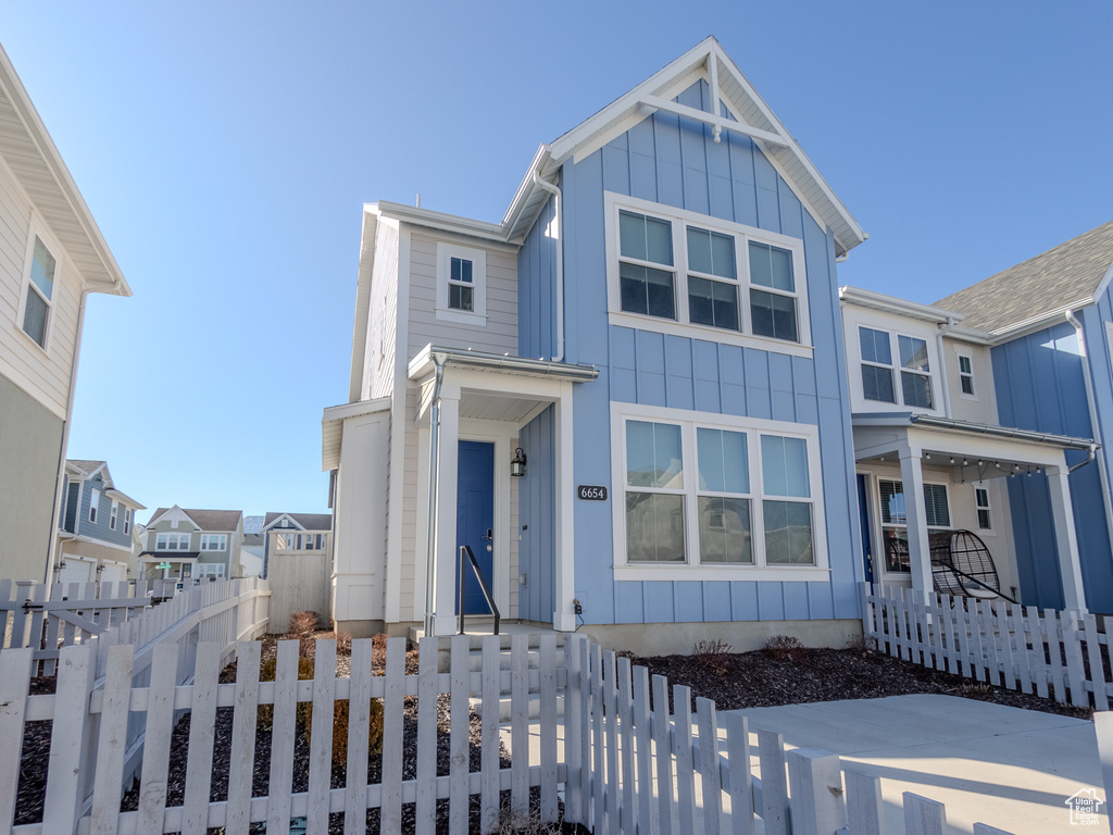 View of front of house featuring board and batten siding, a fenced front yard, and a residential view