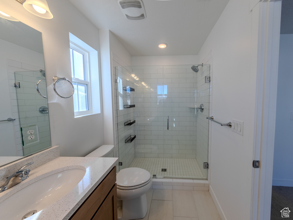 Bathroom with a stall shower, vanity, toilet, tile patterned flooring, and recessed lighting