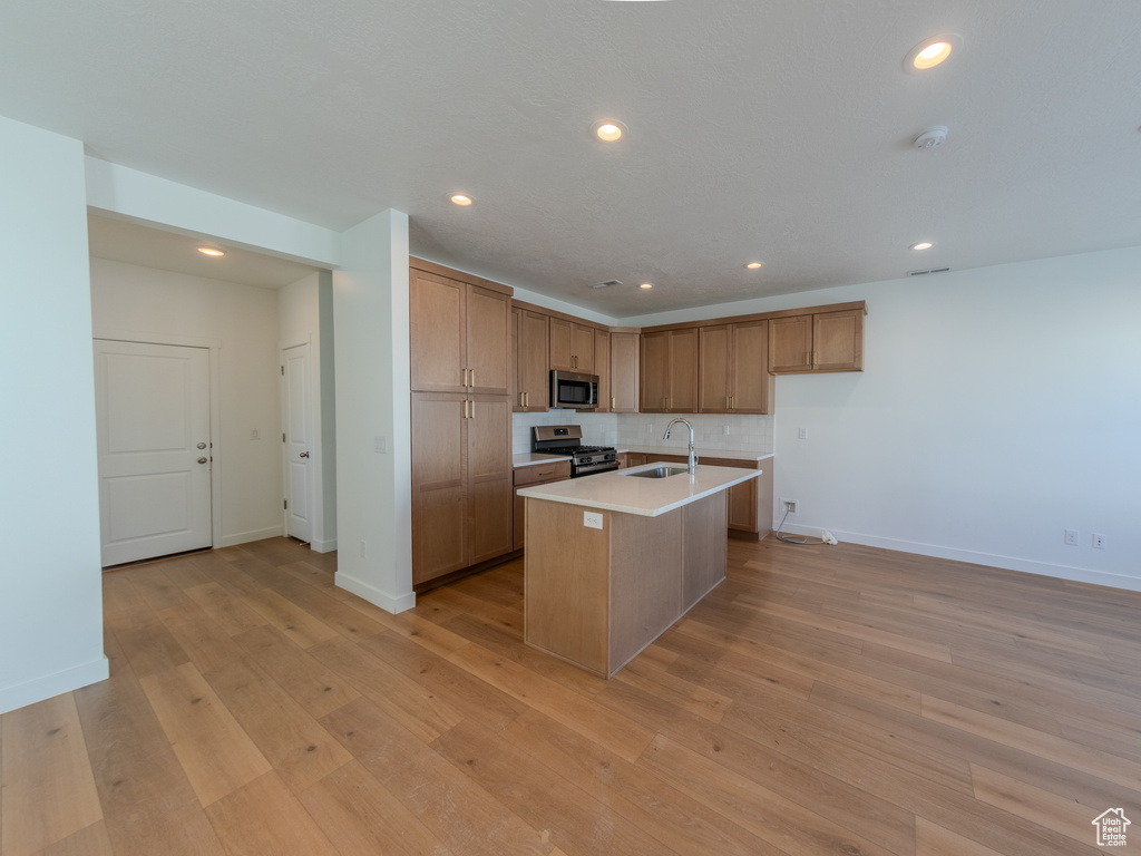 Kitchen featuring appliances with stainless steel finishes, a sink, baseboards, an island with sink, and recessed lighting