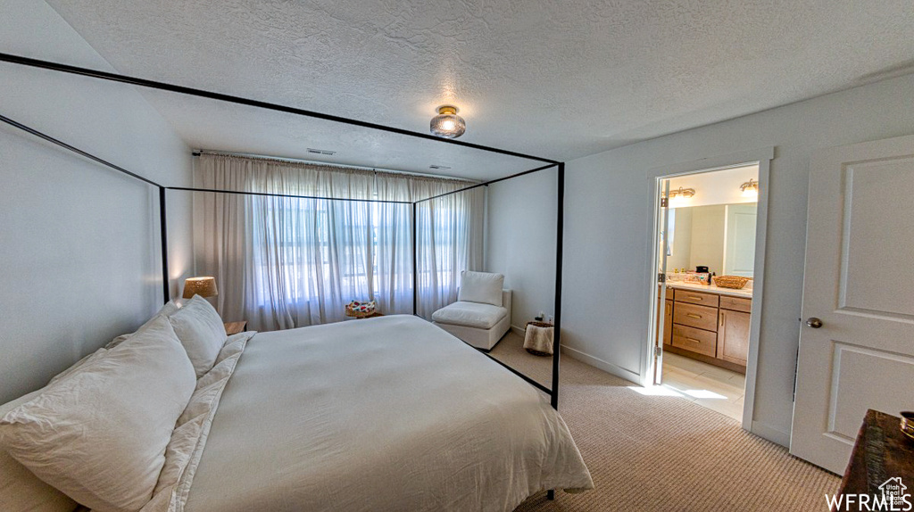 Bedroom featuring light colored carpet, ensuite bath, and baseboards