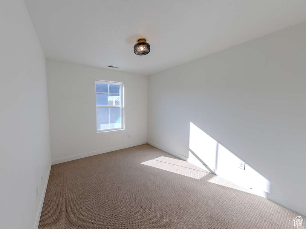Unfurnished room with baseboards and light colored carpet