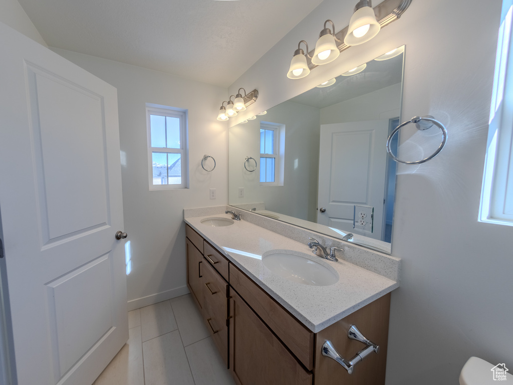 Bathroom featuring double vanity, tile patterned floors, baseboards, and toilet