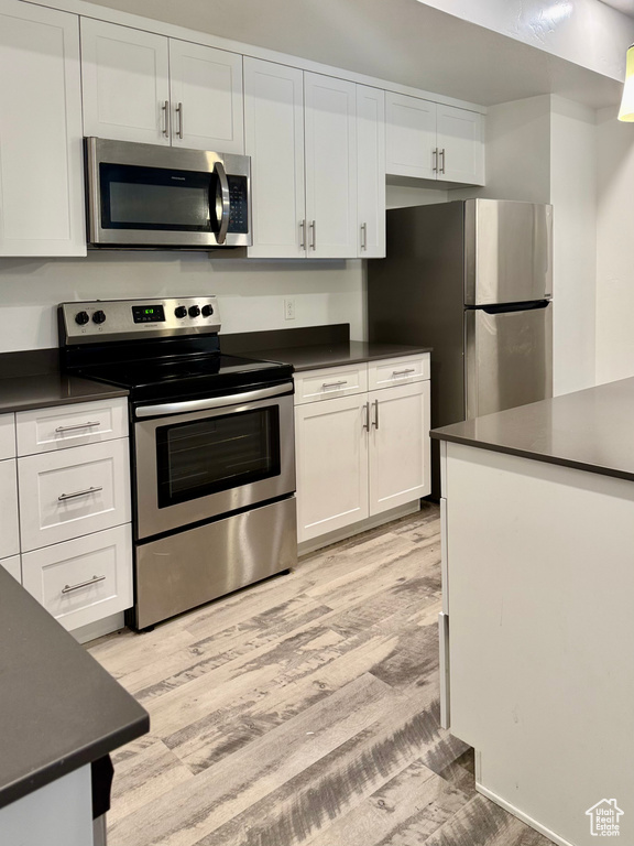 Kitchen featuring appliances with stainless steel finishes, dark countertops, and white cabinetry