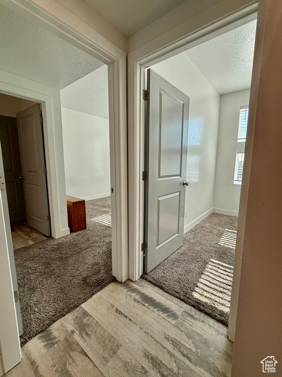 Hall featuring carpet floors, a textured ceiling, and baseboards
