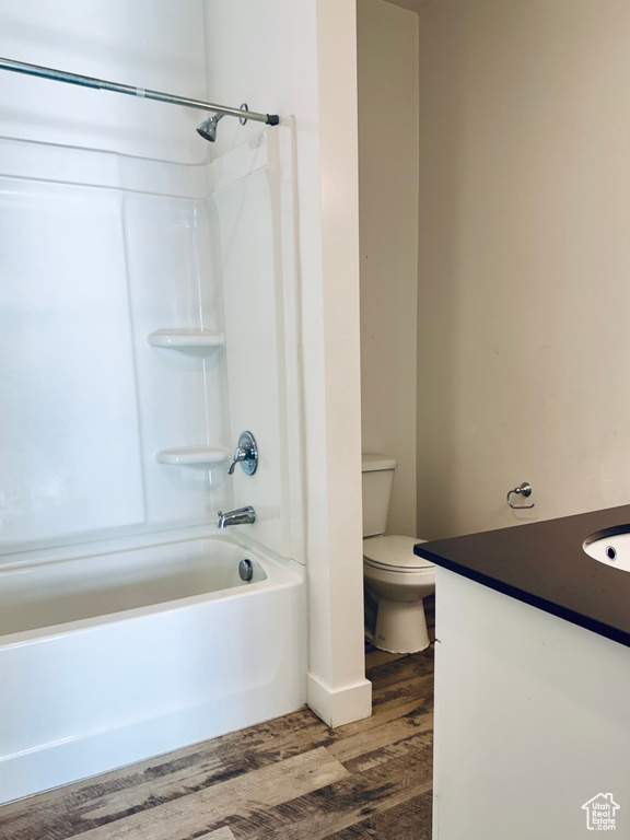 Bathroom featuring vanity, wood finished floors, shower / tub combination, and toilet