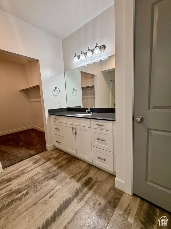 Bathroom with vanity, wood finished floors, a spacious closet, and baseboards