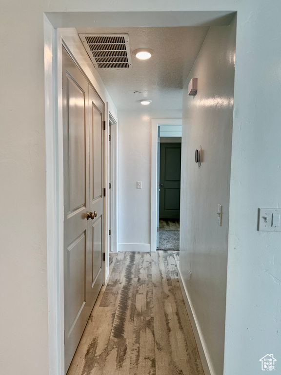 Hall with light wood-type flooring and baseboards