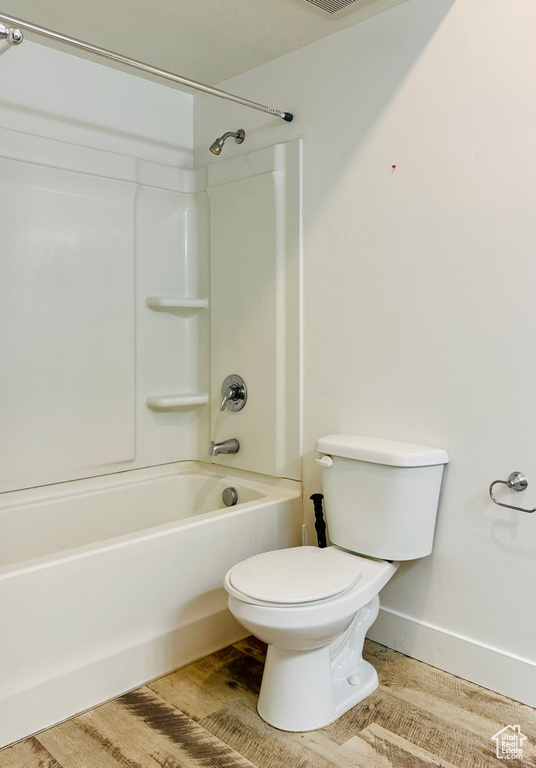 Full bath featuring toilet, shower / washtub combination, and baseboards