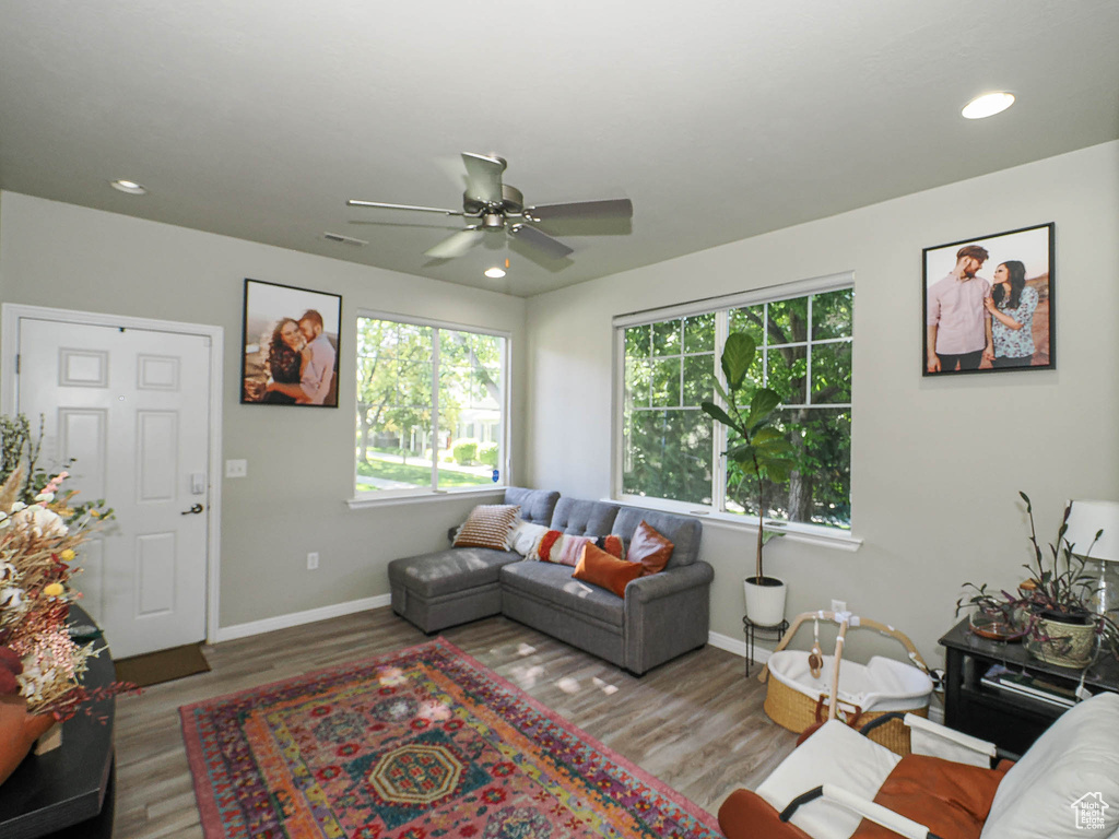 Living room featuring baseboards, wood finished floors, a ceiling fan, and recessed lighting