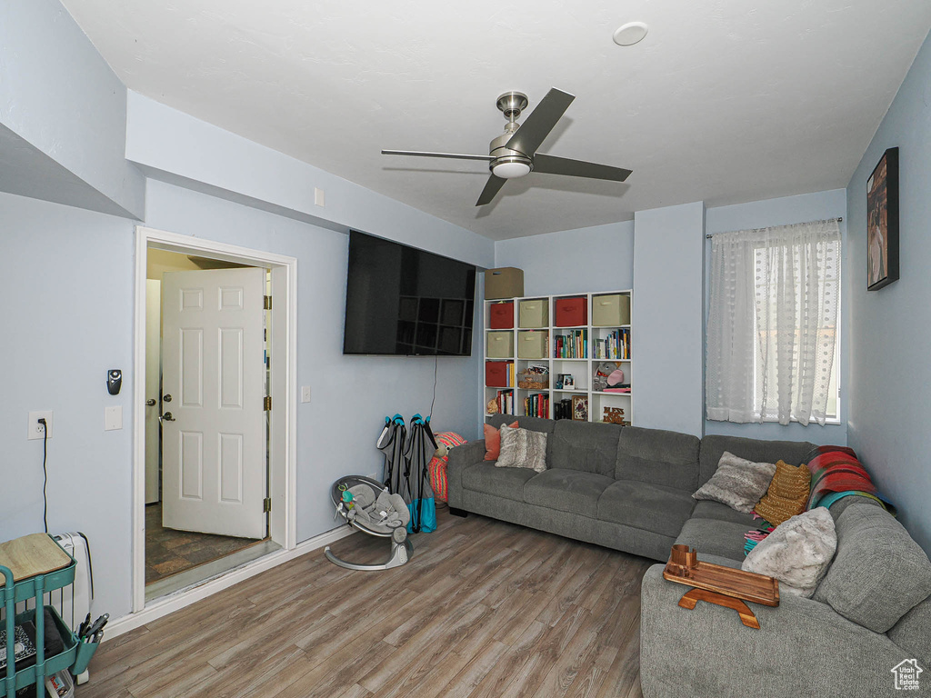 Living room with wood finished floors, a ceiling fan, and baseboards
