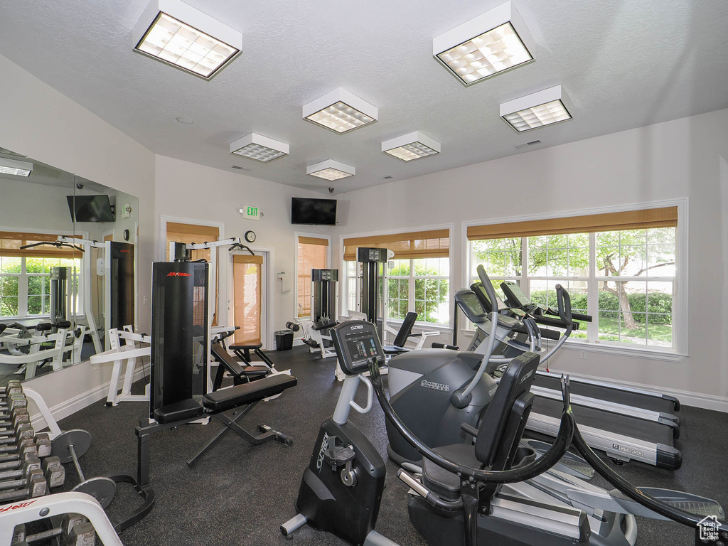 Gym featuring healthy amount of natural light, a textured ceiling, and baseboards