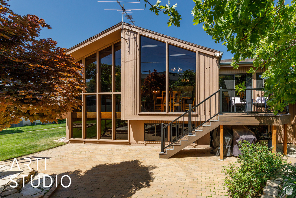 Rear view of property featuring a sunroom, a patio area, and stairs