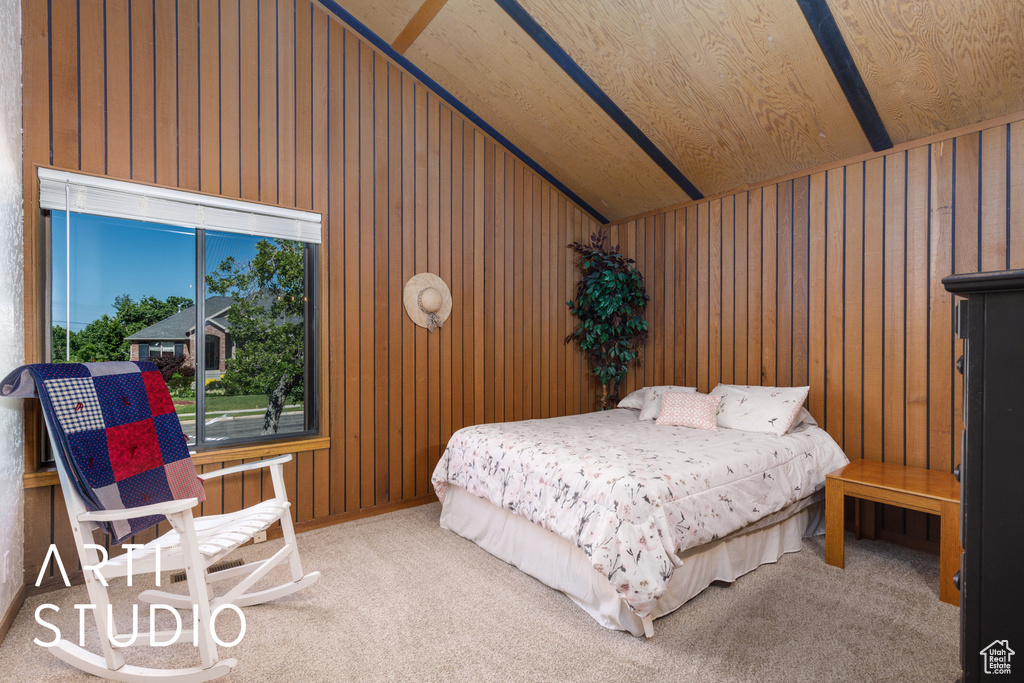 Carpeted bedroom featuring lofted ceiling and wood walls