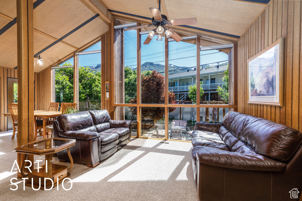 Sunroom / solarium with vaulted ceiling, wood walls, a mountain view, and carpet