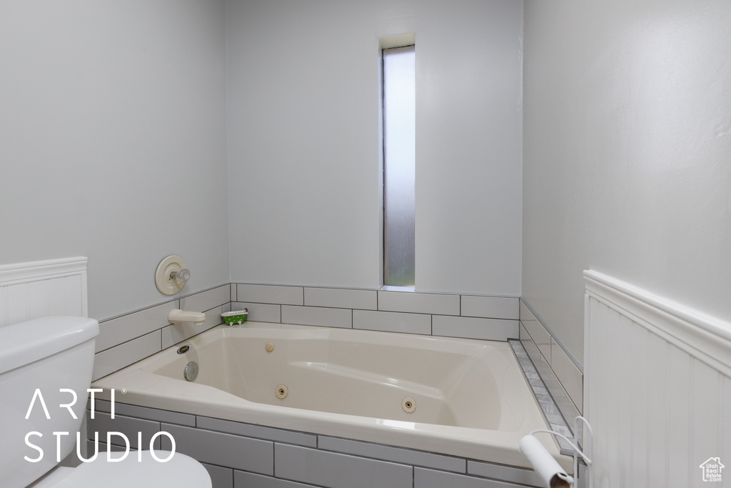 Full bath with toilet and a whirlpool tub